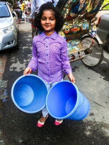 Dhaka, Bangladesh - October 06: Little girl helping carrying two buckets to the people to keep the meat.